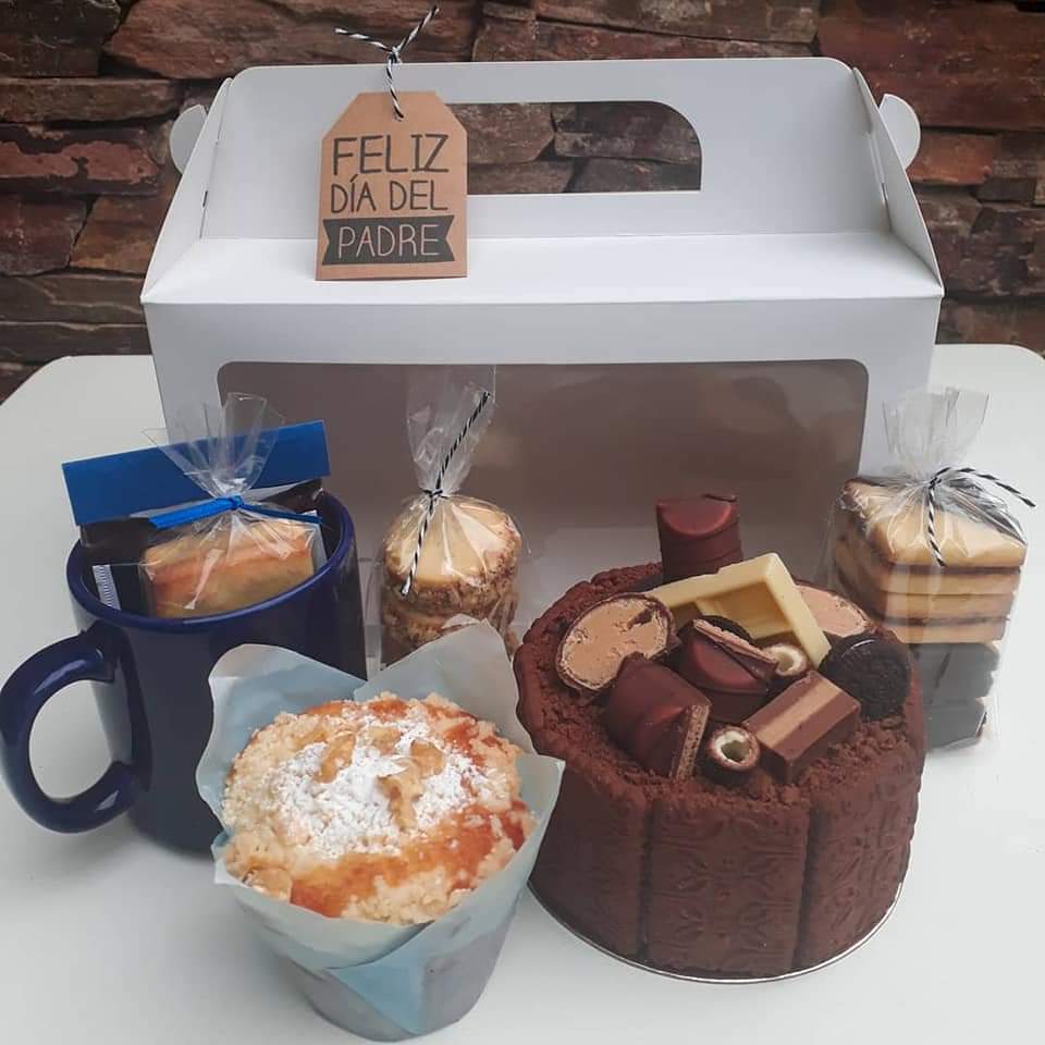 Imagen de caja con muffin de coco, mini cake de chocolate con bombones, galletas de mantequillas y una taza de color azul.