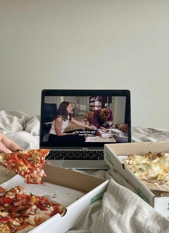 Imagen dedos personas cenando pizza mientras se reproduce una película en una computadora portátil.