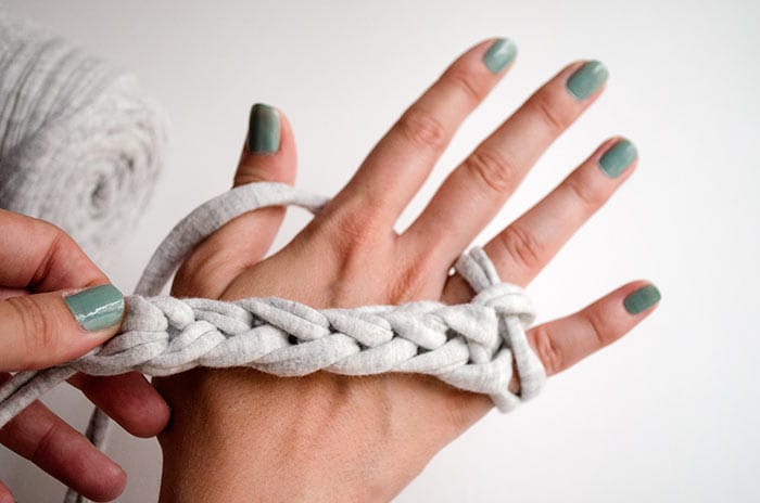 Imagen de mano de una persona que está tejiendo con los dedos.