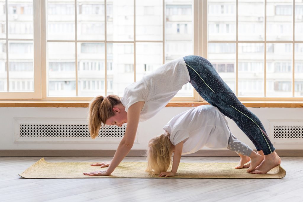 imagen de mujer y niña haciendo una postura de yoga.